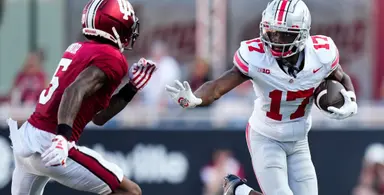 Ohio State player stiff-arms Indiana defender in college football matchup.