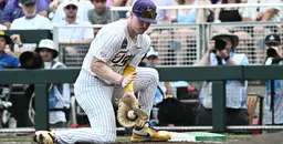 LSU baseball player fielding a ground ball at first base during a College World Series 2025 game