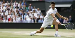Tennis player hitting a low forehand shot on grass during the Wimbledon Championships