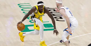 Indiana Pacers player dribbling the basketball while being closely guarded by an Oklahoma City Thunder defender during an NBA game.
