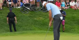 Scheffler putting on the green with a crowd of spectator