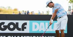 Golfer in light blue patterned shirt and white shorts taking a swing in front of a LIV Golf Dallas Championship sign