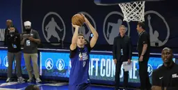 Cooper Flagg taking a jump shot during the NBA Draft Combine, with scouts and officials observing in the background.