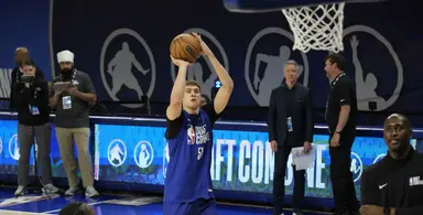 Cooper Flagg taking a jump shot during the NBA Draft Combine, with scouts and officials observing in the background.